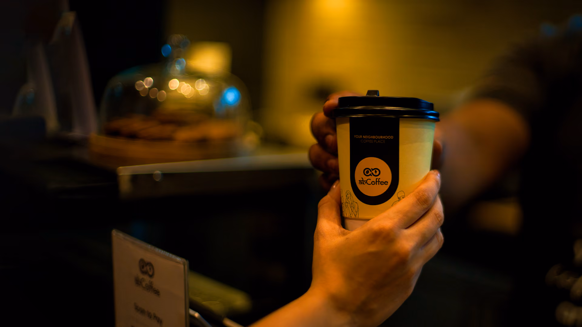 A guest holding an AB Coffee cup at a deck